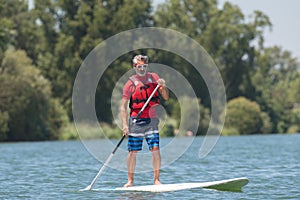 Man enjoying ride on lake with paddleboard