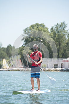 Man enjoying ride on lake with paddleboard