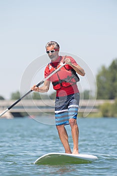 Man enjoying ride on lake with paddleboard