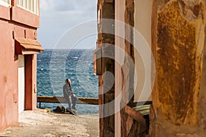 A man enjoying the sun and the ocean sitting on the seaside railing in Pozo Izquierdo, Canary Islands, Spain photo