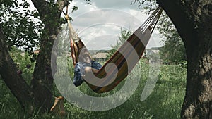 Man enjoying vacation and swinging in hammock. Relax in hammock. Camping. Male lying in hammock at garden. Male swinging in hammoc