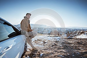 man enjoying the view of cappadocia in winter sitting at the front of his car