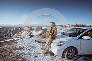 man enjoying the view of cappadocia in winter sitting at the front of his car