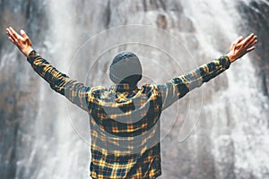Man enjoying waterfall raised hands