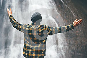 Man enjoying waterfall raised hands