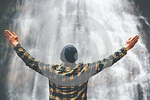 Man enjoying waterfall raised hands