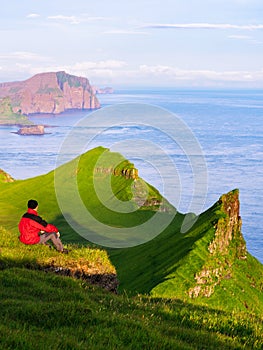 A man enjoys a beautiful view from Mykines, Faroe Islands