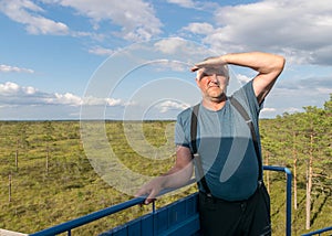 A man enjoys the swamp landscape from the spectator tower in the swamp, the summer landscape
