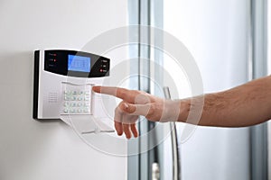 Man entering code on home security system near door, closeup