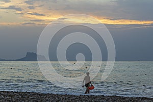 Man entering the water to swim at sunrise on the beach of Albir