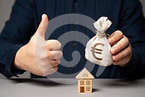 A man with a euro money bag approves a real estate deal. Buy or sell a house.