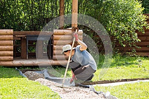 Man evens gravel on path with rake