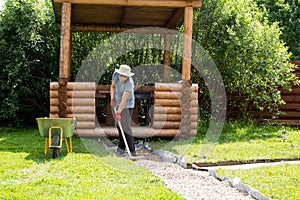 Man evens gravel on path with rake