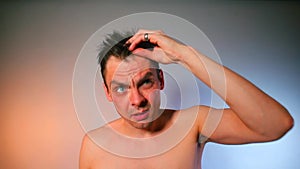 A man examines his bald patches in the bathroom mirror