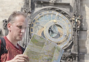 Man examines the map on background of historical medieval astronomical Clock on the Old