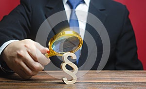 A man examines a paragraph figure with a magnifying glass. Studying laws and legislation, norms, rules. Legal service, lawyer photo