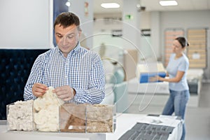 Man examines samples of mattress fillers in furniture store