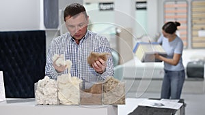 Man examines samples of mattress fillers in furniture store