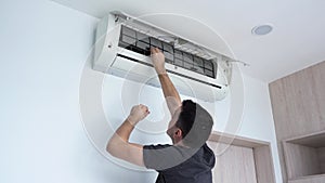 A man examines a terribly dirty air conditioning filter. He removed the filter from the air conditioner and twists it in his hands