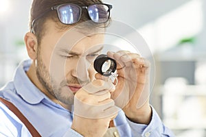 Man examining diamond ring through magnifying loupe, checking gemstone quality and authenticity. photo