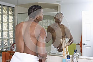Man Examining Himself In Bathroom Mirror
