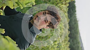 Man examining vine bush at vineyard harvesting vertical closeup. Winegrowing