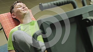 A man with excess weight doing leg presses on the simulator in the gym. Fitness training. Healthy lifestyle concept