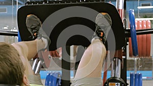 A man with excess weight doing leg presses on the simulator in the gym. Fitness training. Healthy lifestyle concept