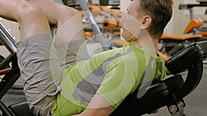 A man with excess weight doing leg presses on the simulator in the gym. Fitness training. Healthy lifestyle concept