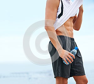 Man, exercise and abs with water bottle, body building and muscle growth and development in outdoor. Male athlete