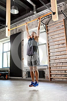 Man exercising on bar and doing pull-ups in gym