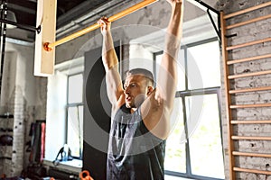 Man exercising on bar and doing pull-ups in gym