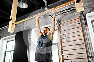 Man exercising on bar and doing pull-ups in gym