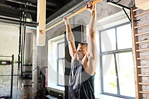 Man exercising on bar and doing pull-ups in gym