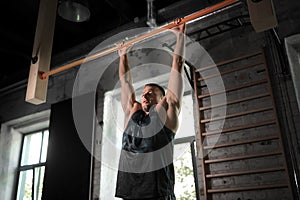 man exercising on bar and doing pull-ups in gym