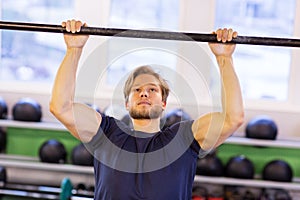 Man exercising on bar and doing pull-ups in gym