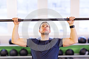 Man exercising on bar and doing pull-ups in gym