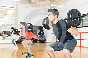 Man Exercising With Barbell In Health Club