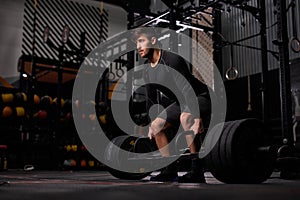 Man exercising with barbell. Male bodybuilder doing weight lifting workout at dark gym