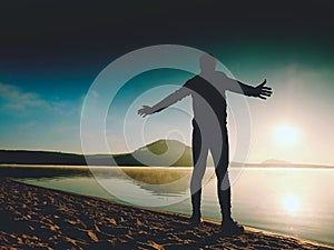 Man exercising on beach. Silhouette of active man exercising and stretching at lake