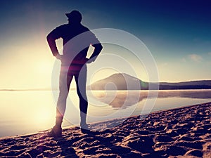 Man exercising on beach. Silhouette of active man exercising and stretching at lake