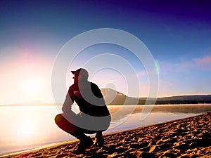 Man exercising on beach. Silhouette of active man exercising and stretching at lake