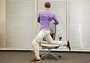 Man exercising on chair in office