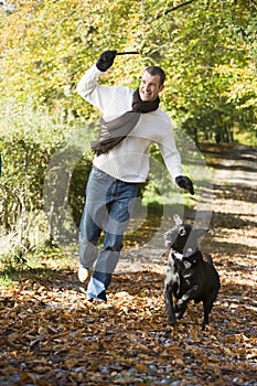 Man exercising dog in woodland