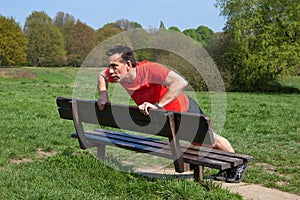 Man Exercising doing PressUps on a Park Bench