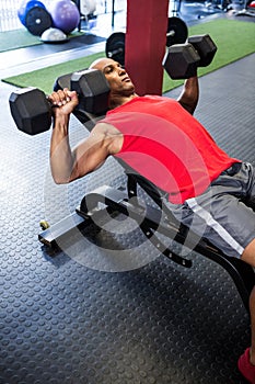 Man exercising with dumbbells on bench