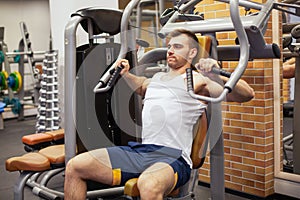 Man exercising at gym. Fitness athlete doing chest exercises on vertical bench press machine