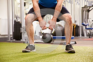 Man exercising in a gym with a kettlebell weight, crop