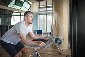 Man exercising in the gym riding stationary bike indoor cycling