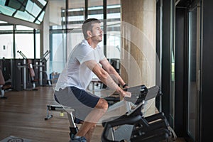 Man exercising in the gym riding stationary bike indoor cycling